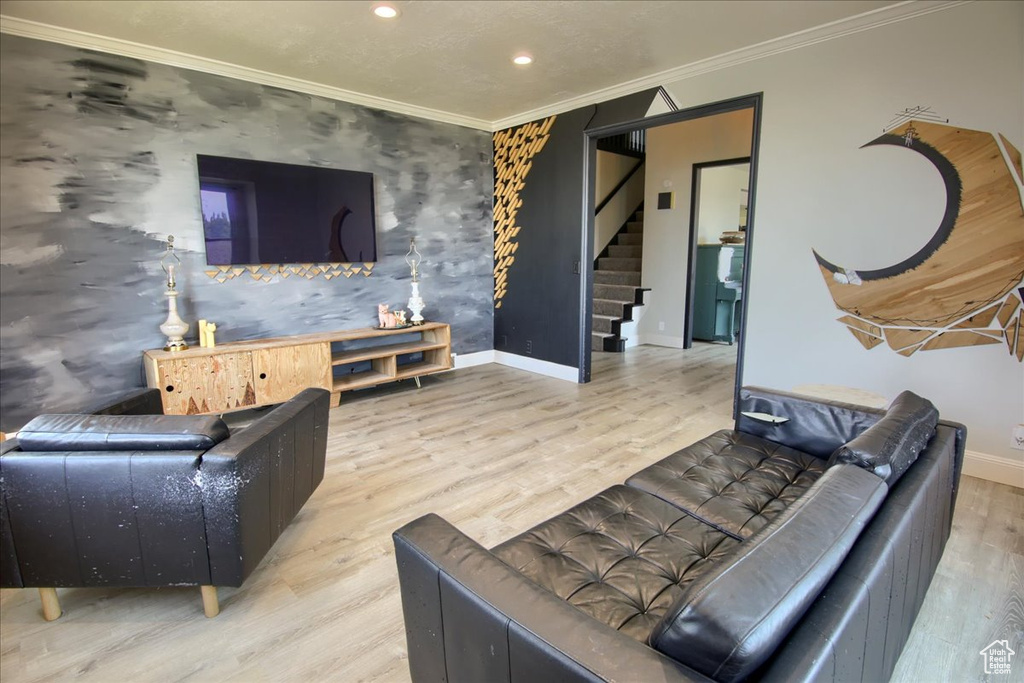 Living area with stairway, ornamental molding, an accent wall, recessed lighting, and wood finished floors