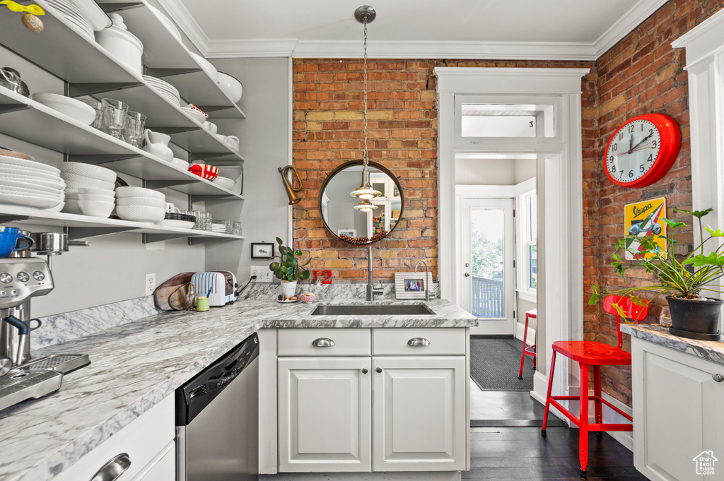 Kitchen featuring stainless steel dishwasher, brick wall, crown molding, white cabinetry, and dark wood-style flooring