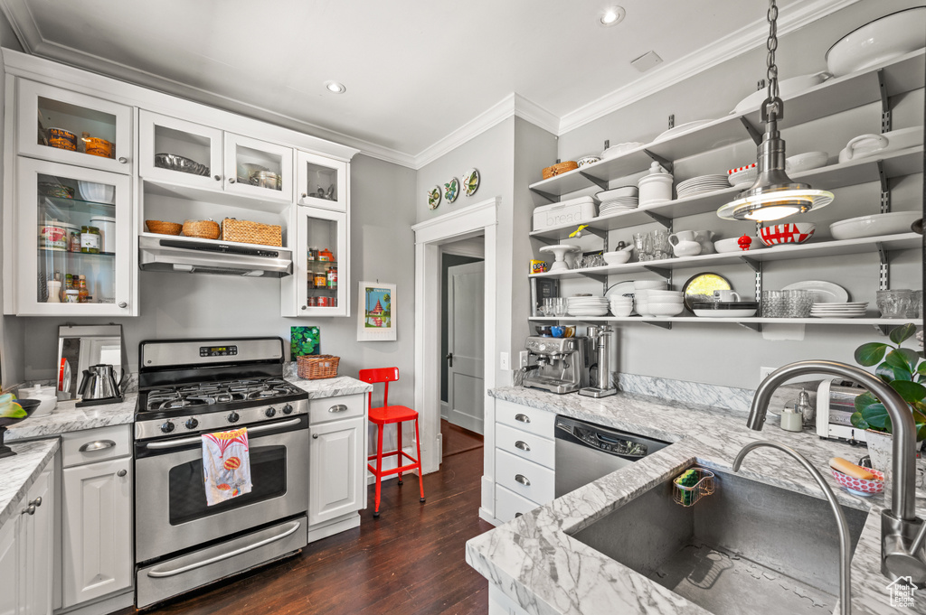 Kitchen with stainless steel gas range, under cabinet range hood, dishwashing machine, open shelves, and crown molding