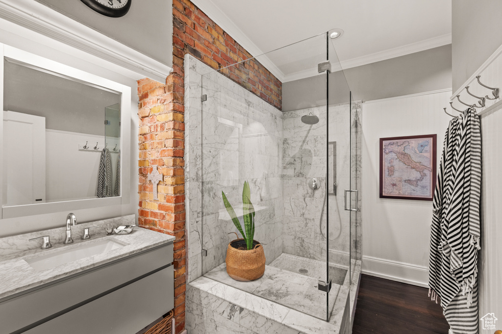 Bathroom with a stall shower, crown molding, vanity, and wood finished floors