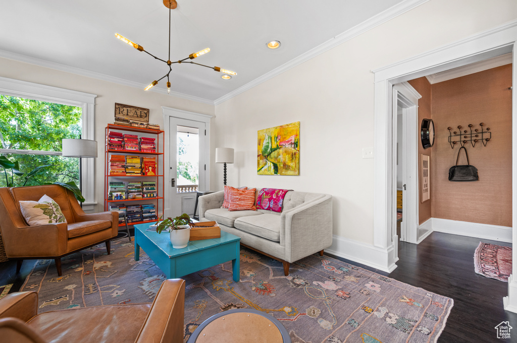 Living area with a chandelier, crown molding, and wood finished floors