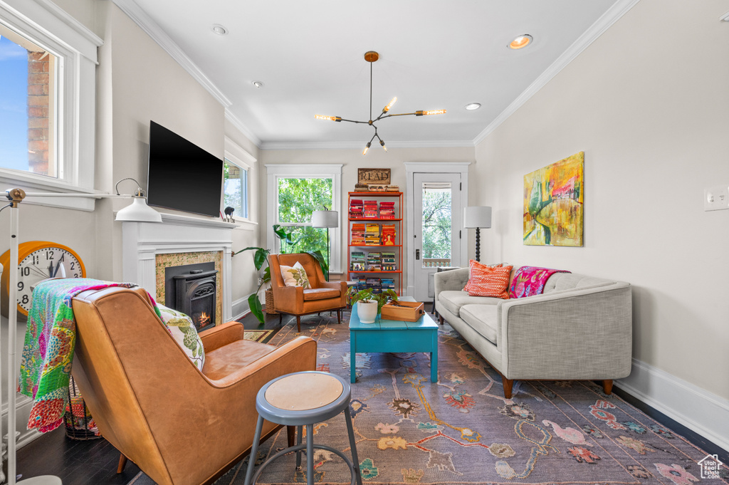 Living area with a chandelier, crown molding, a glass covered fireplace, recessed lighting, and wood finished floors