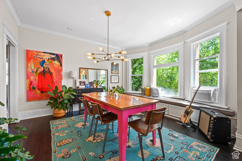 Dining room with dark wood-type flooring, a chandelier, and ornamental molding