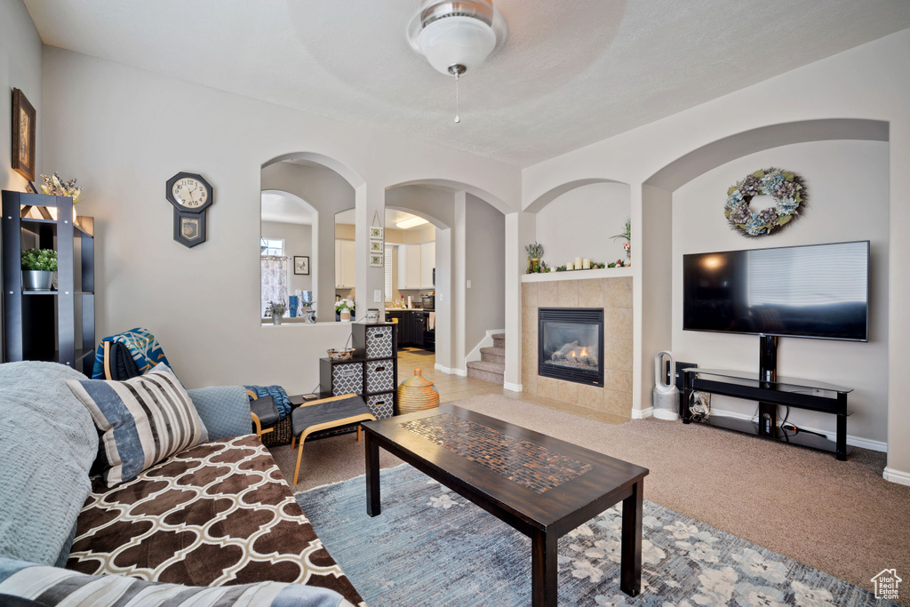 Living area with a tile fireplace, light colored carpet, and arched walkways