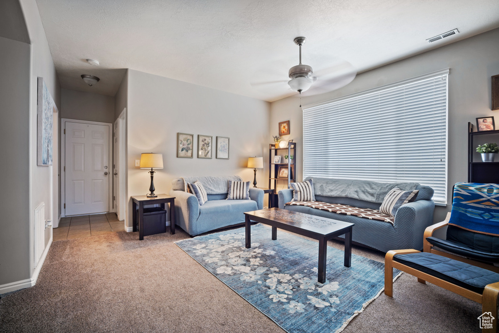 Carpeted living area with a ceiling fan and baseboards