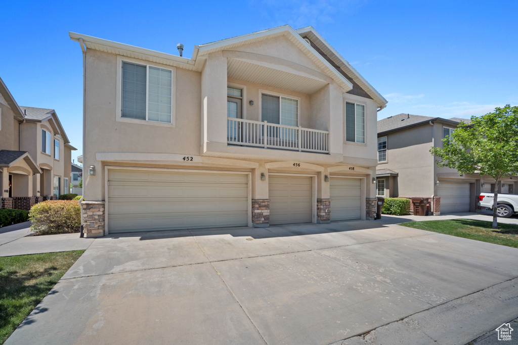 View of property featuring stone siding, an attached garage, stucco siding, and driveway