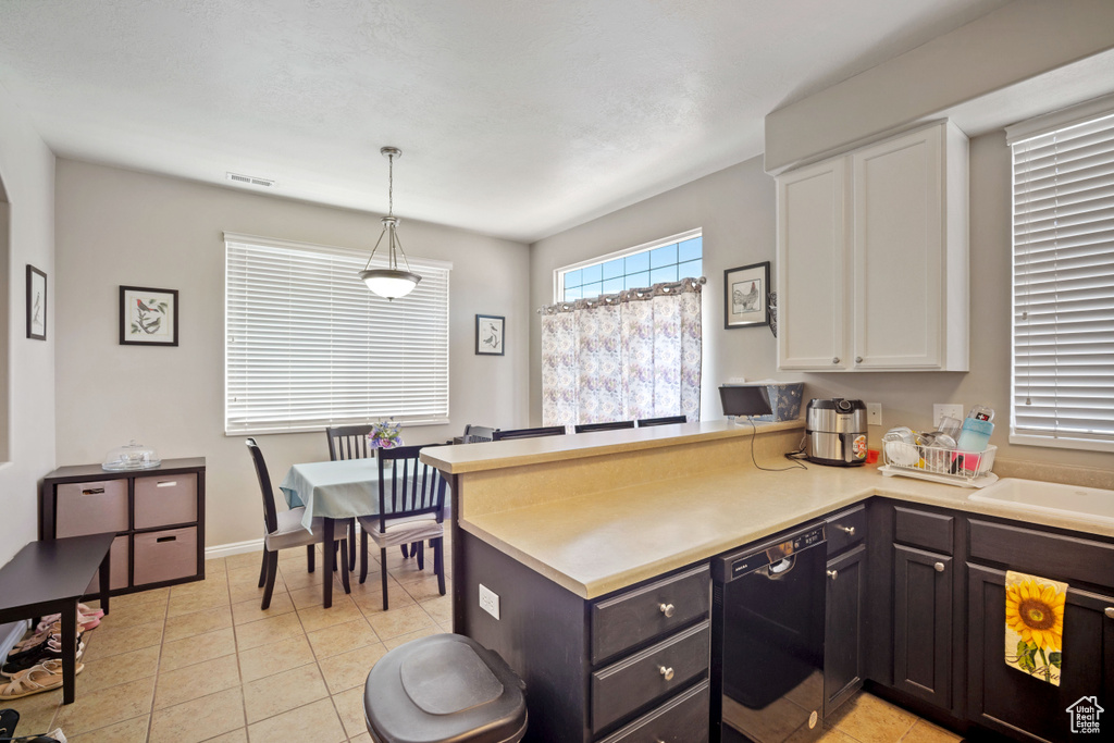 Kitchen with black dishwasher, white cabinetry, a peninsula, and light tile patterned floors
