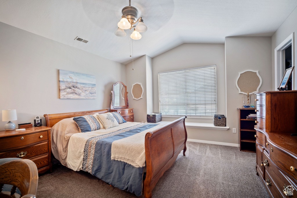 Bedroom featuring dark carpet, lofted ceiling, and a ceiling fan