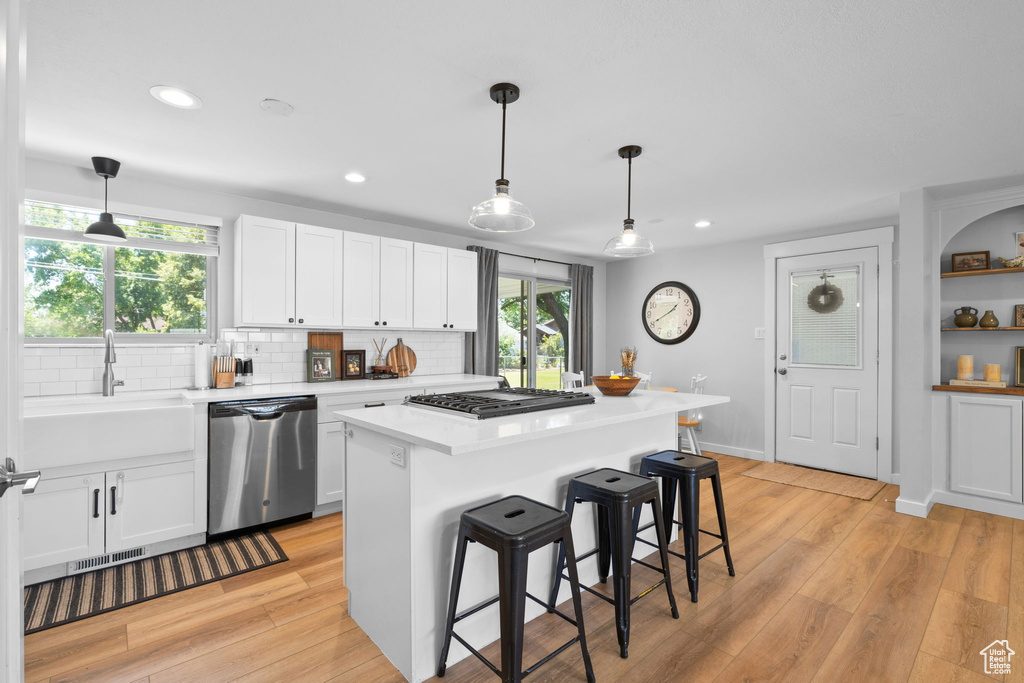 Kitchen featuring stainless steel appliances, white cabinetry, light countertops, decorative backsplash, and recessed lighting