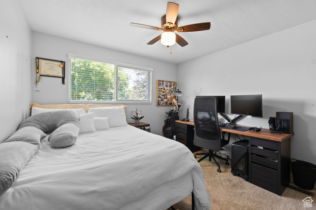 Bedroom featuring light colored carpet, a desk, and a ceiling fan