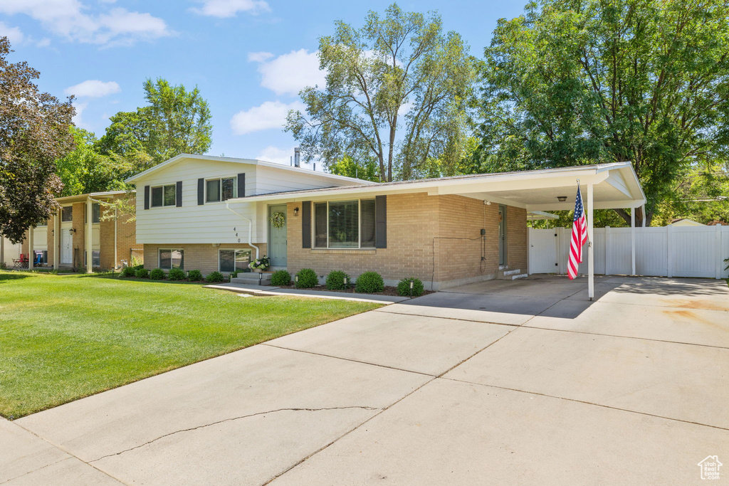 Split level home featuring brick siding, concrete driveway, and a carport