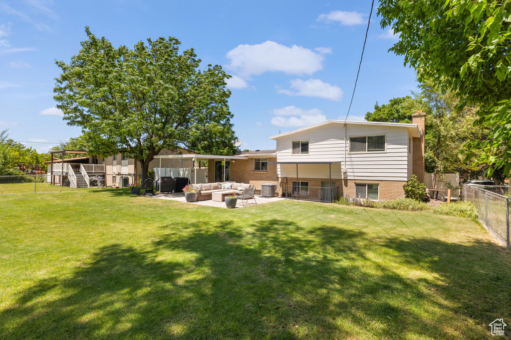 Back of property with an outdoor living space, a fenced backyard, a chimney, brick siding, and a patio area