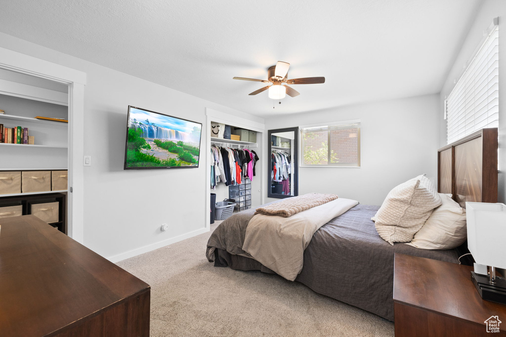 Bedroom with a tile fireplace, carpet, a closet, and a ceiling fan