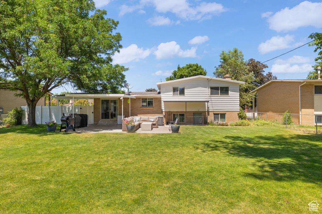 Back of house featuring outdoor lounge area, a patio, a fenced backyard, a chimney, and brick siding