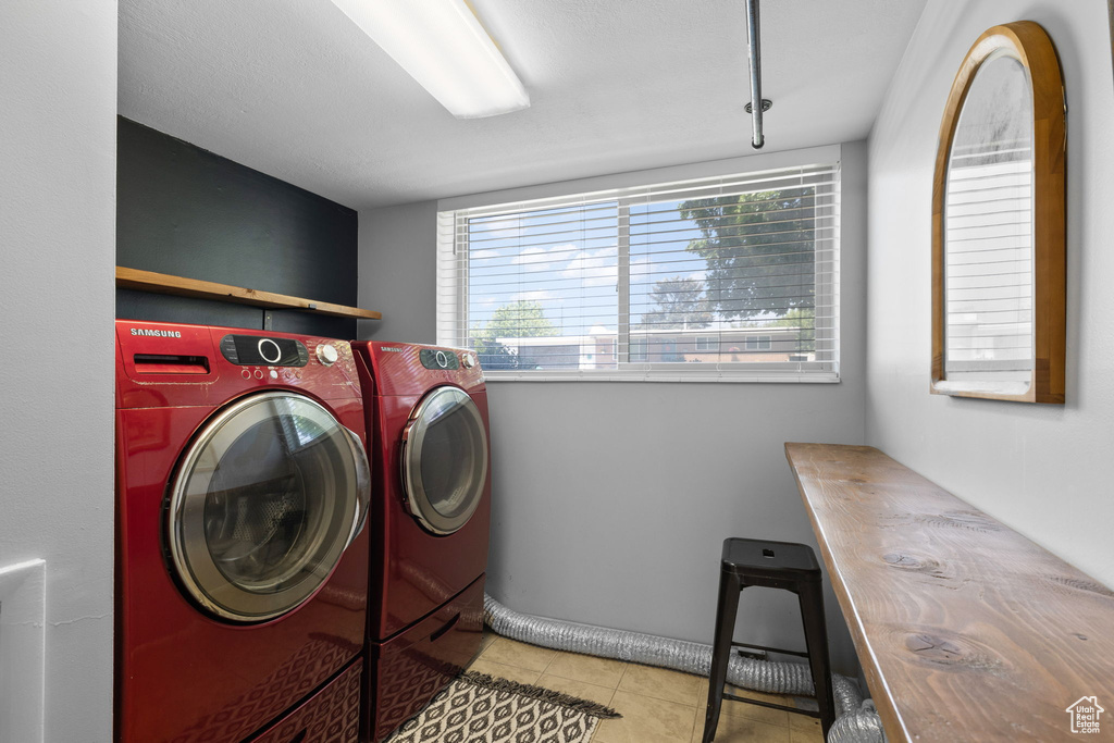 Washroom featuring tile patterned flooring and washing machine and dryer