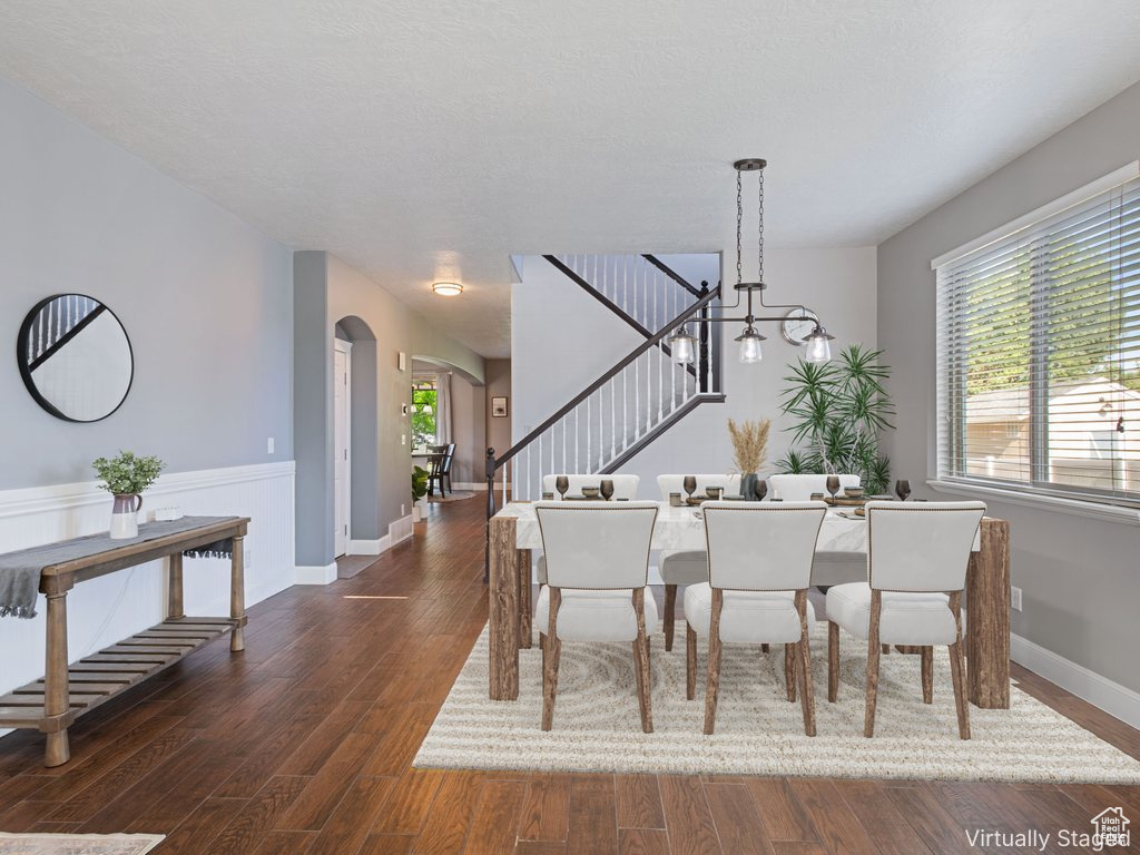 Dining room with stairway, arched walkways, dark wood-style floors, and plenty of natural light