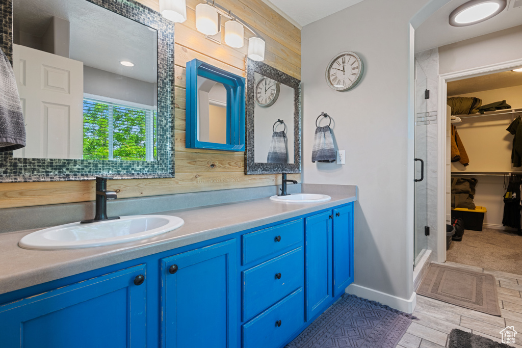 Full bath featuring a walk in closet, a shower stall, and double vanity