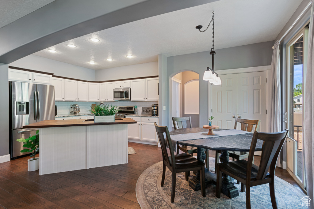 Dining room with arched walkways, dark wood-type flooring, and recessed lighting