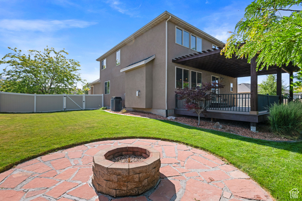 Rear view of house featuring a fire pit, stucco siding, a patio area, a gate, and a wooden deck