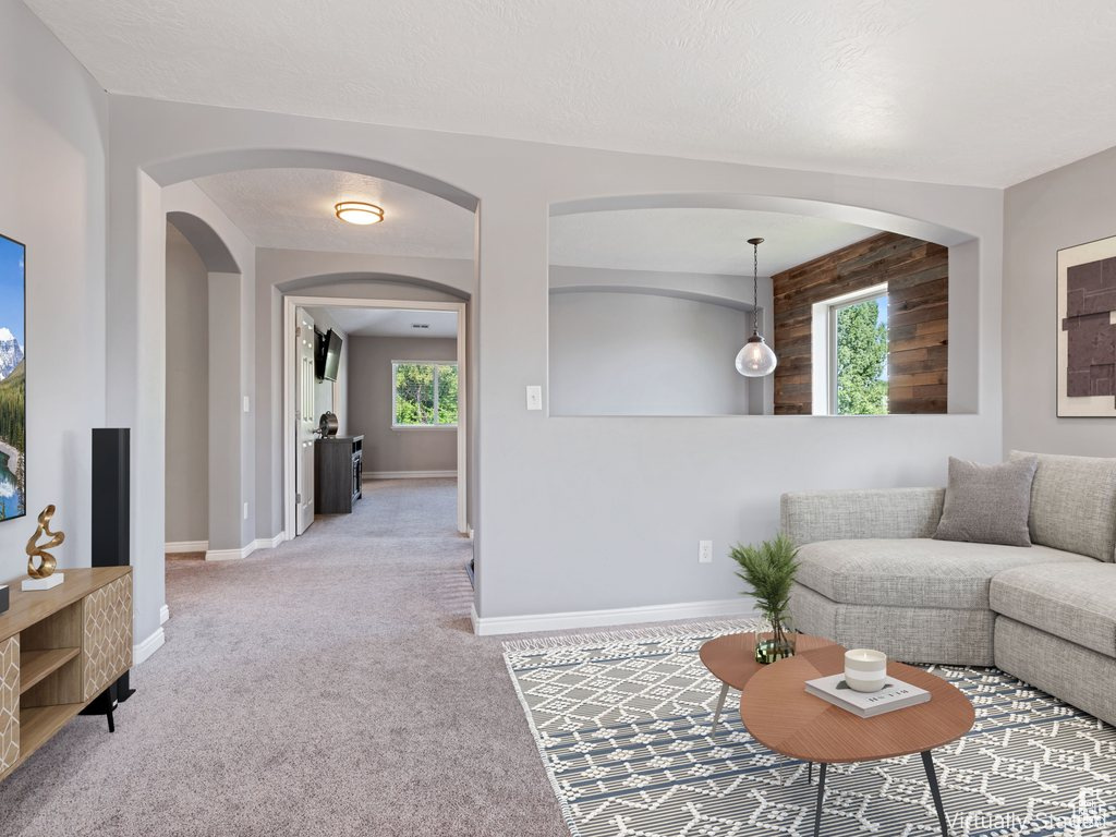 Living area featuring plenty of natural light, arched walkways, and light colored carpet
