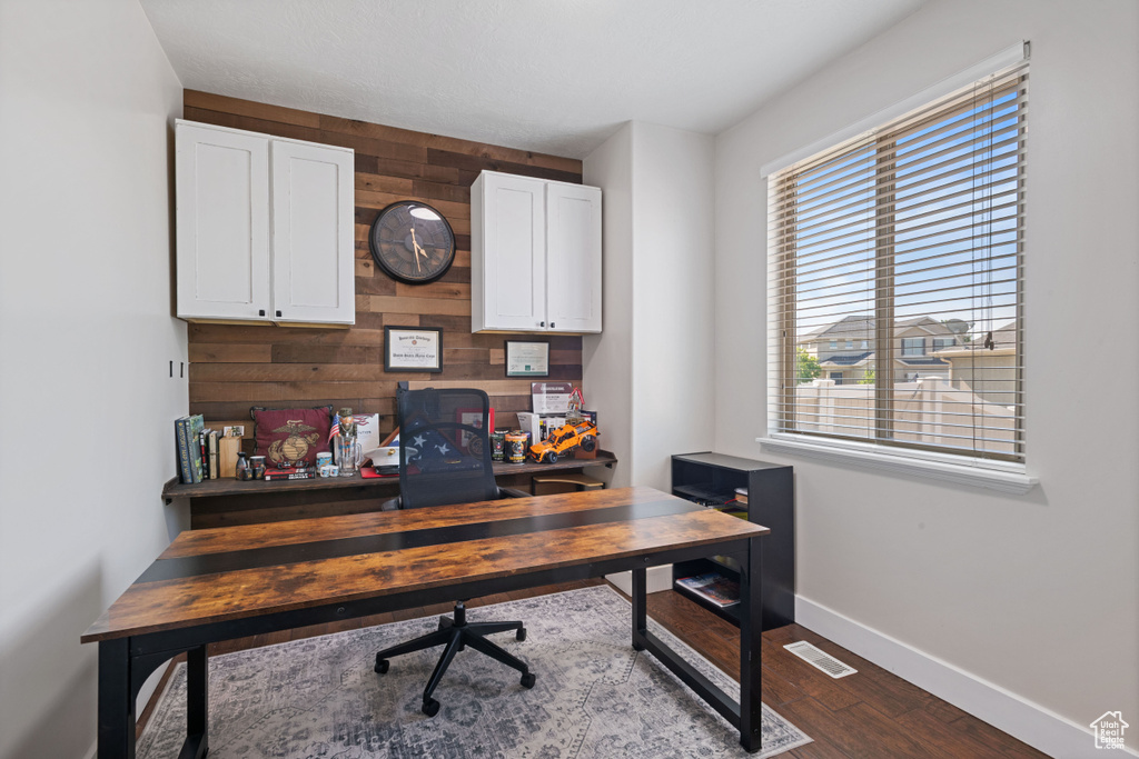 Office area with dark wood-style flooring and wood walls