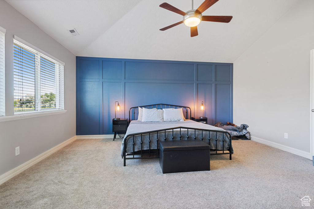 Carpeted bedroom featuring lofted ceiling, a decorative wall, and ceiling fan