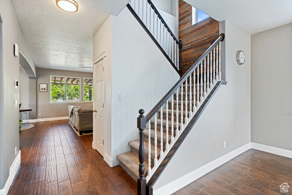 Stairs with wood finished floors, a textured ceiling, and arched walkways