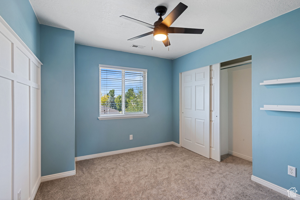 Unfurnished bedroom featuring carpet, ceiling fan, and a closet