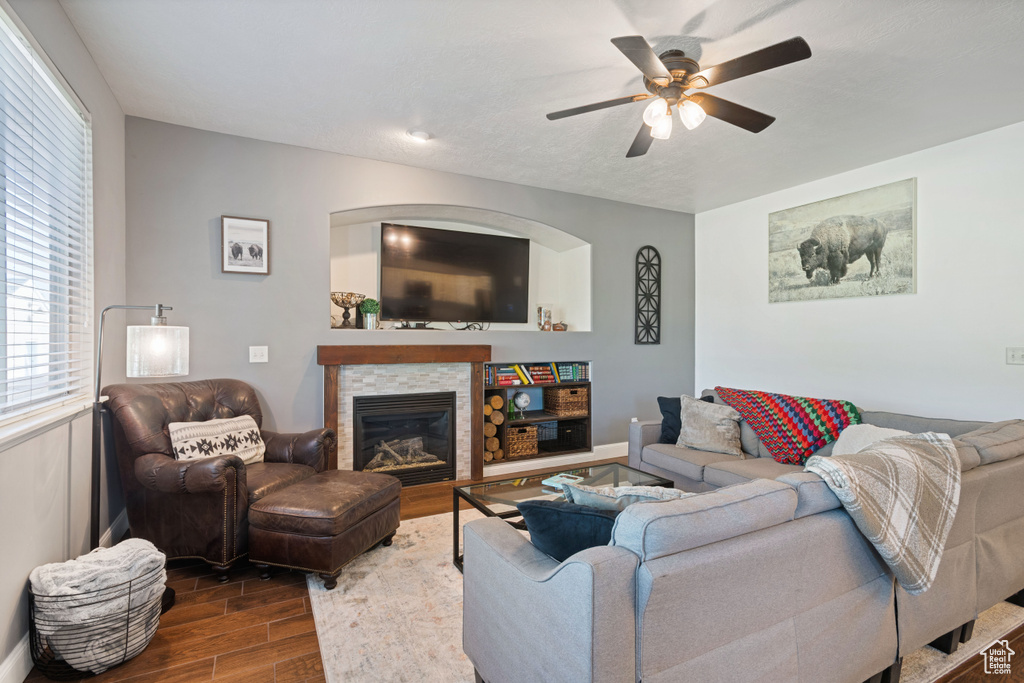 Living room with dark wood-style flooring, ceiling fan, and a glass covered fireplace