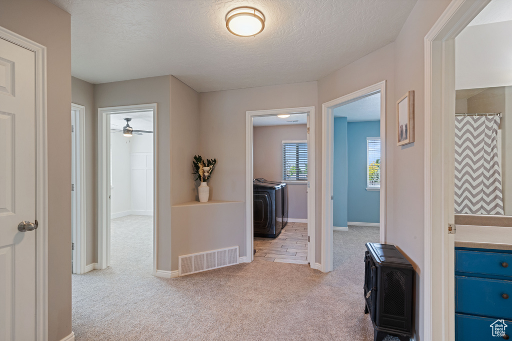 Hallway featuring light carpet, a textured ceiling, and washer / clothes dryer