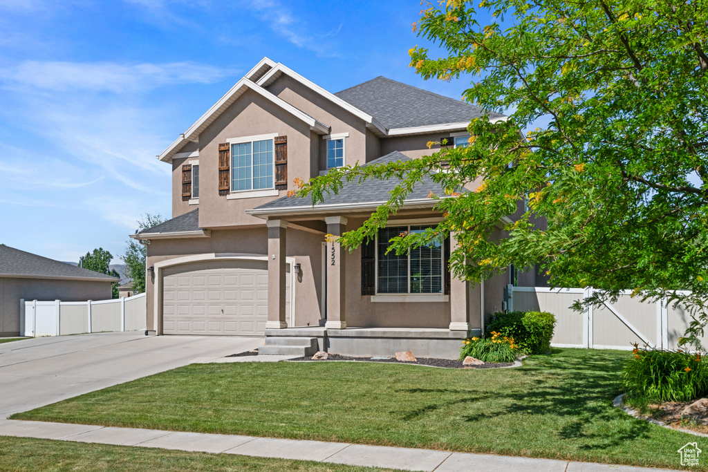View of front of property with an attached garage, driveway, stucco siding, a gate, and roof with shingles