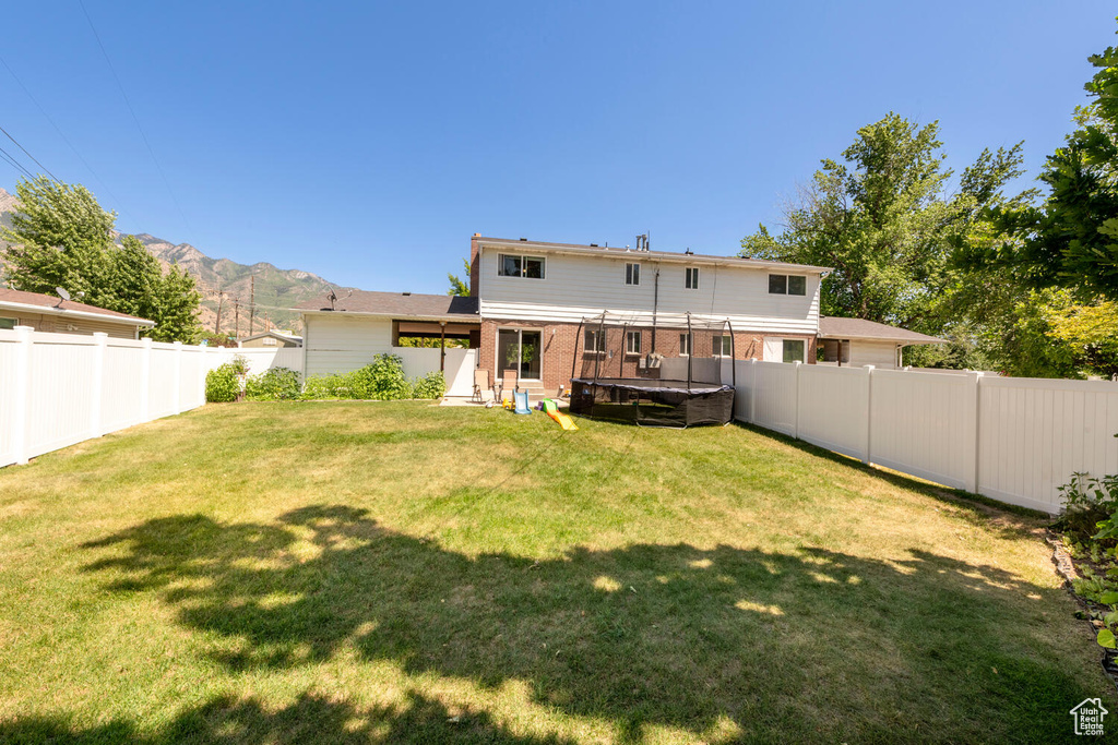 Back of house featuring a hot tub, a fenced backyard, brick siding, and a mountain view