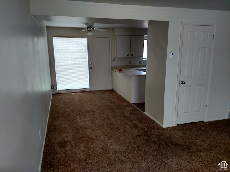 Kitchen with carpet, white cabinets, ceiling fan, and light countertops