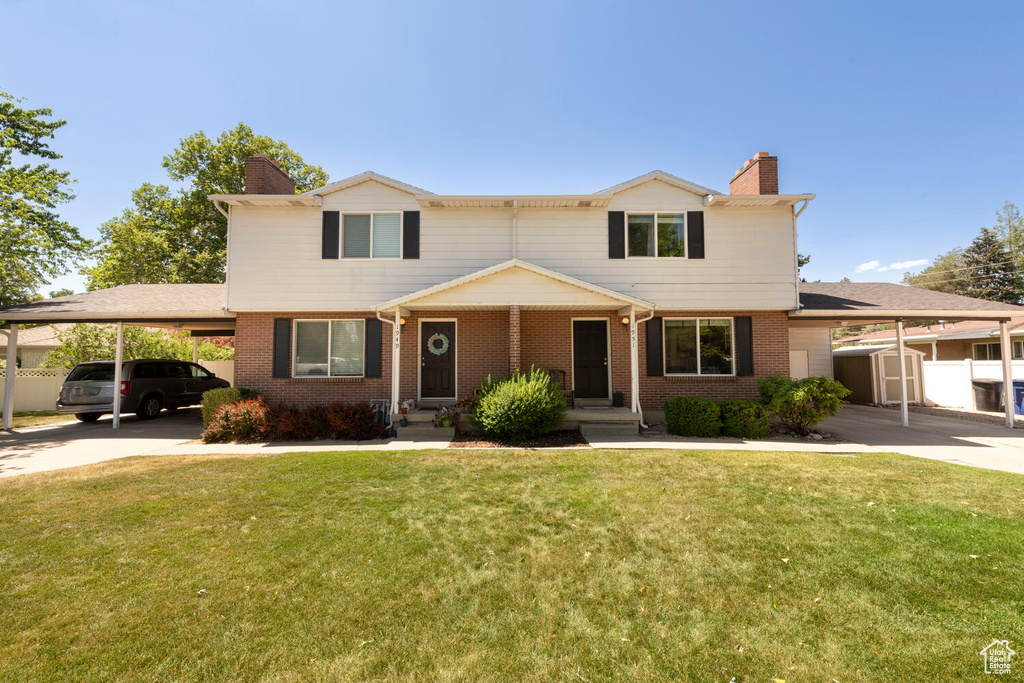 View of front of house with a chimney, an attached carport, and driveway