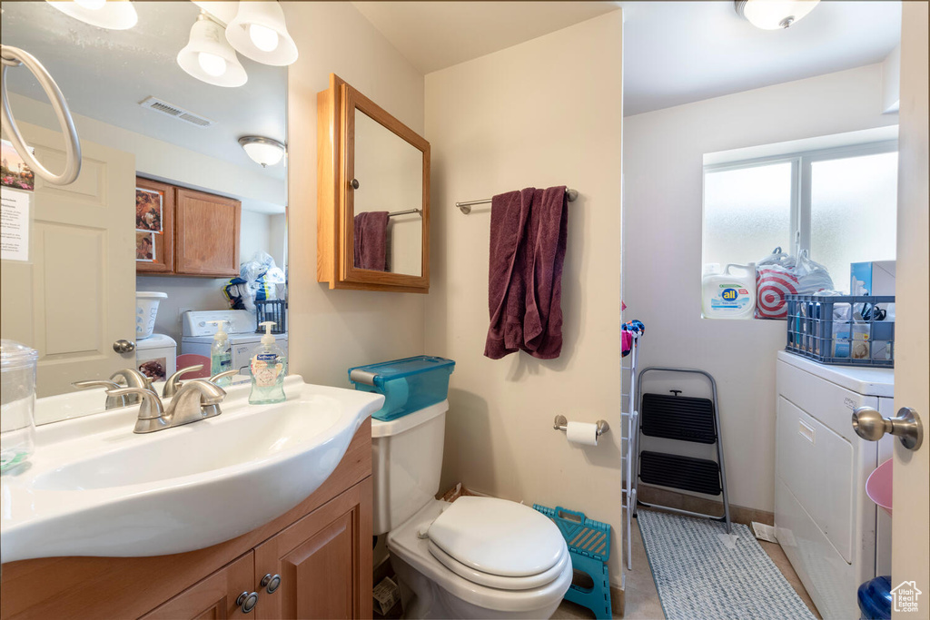Bathroom featuring vanity, heating unit, and washer and clothes dryer