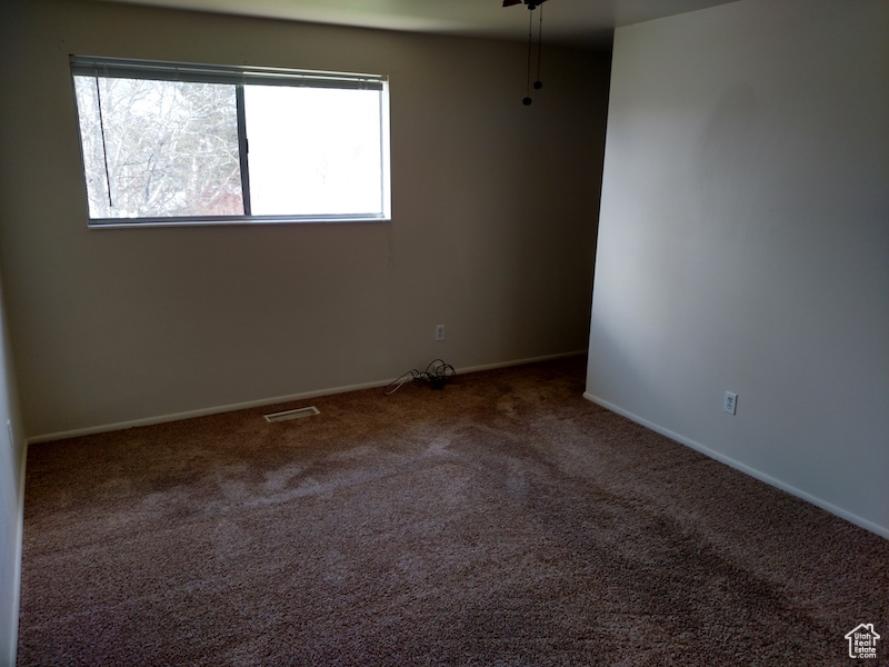 Carpeted spare room featuring baseboards