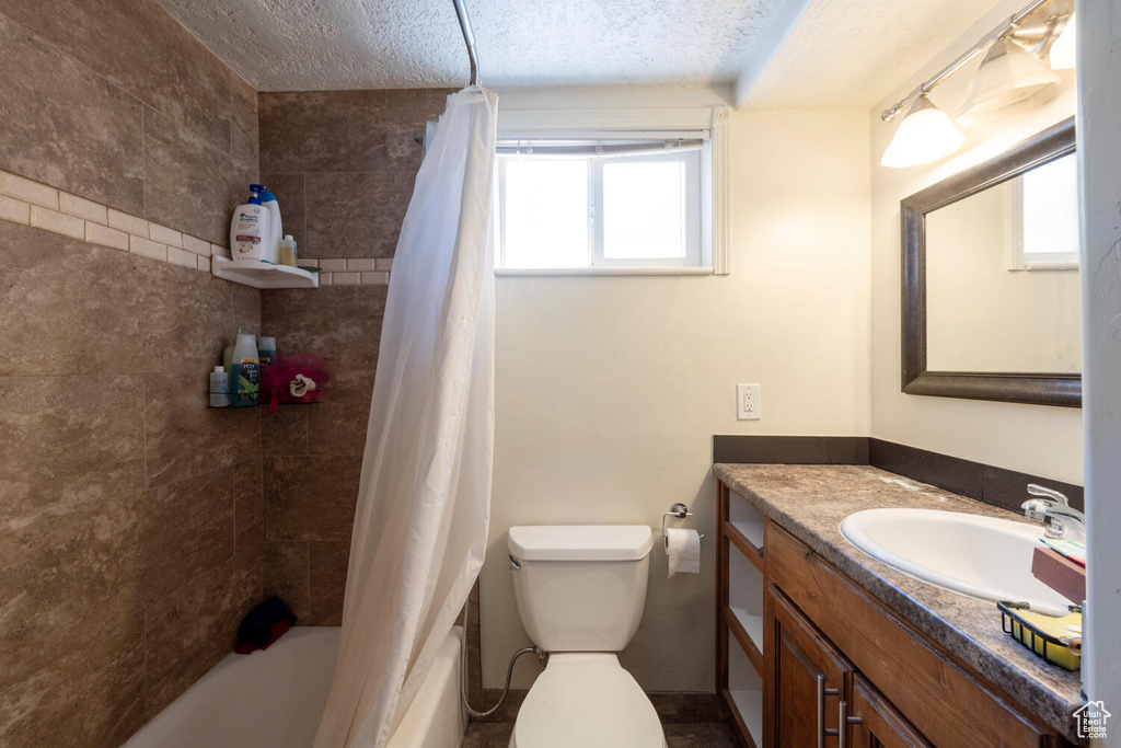 Bathroom with vanity, shower / bath combination with curtain, and a textured ceiling