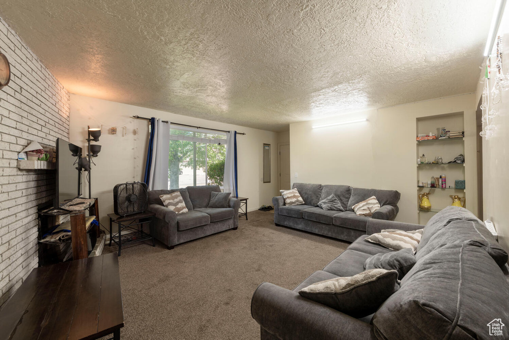 Carpeted living area featuring a textured ceiling and brick wall