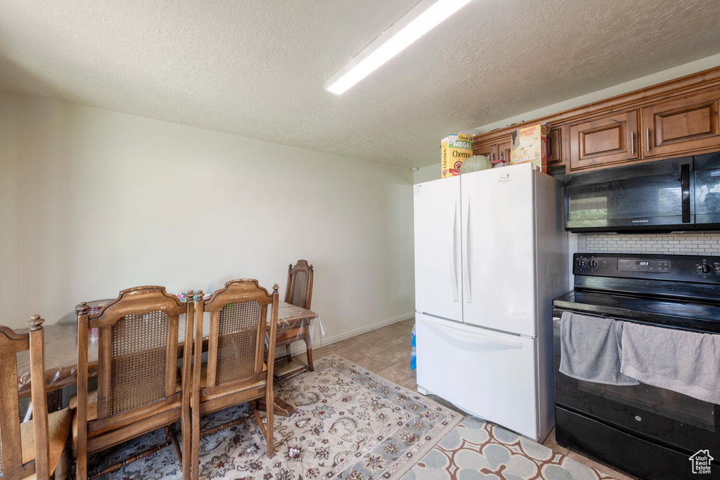 Kitchen featuring black appliances, brown cabinets, and a textured ceiling
