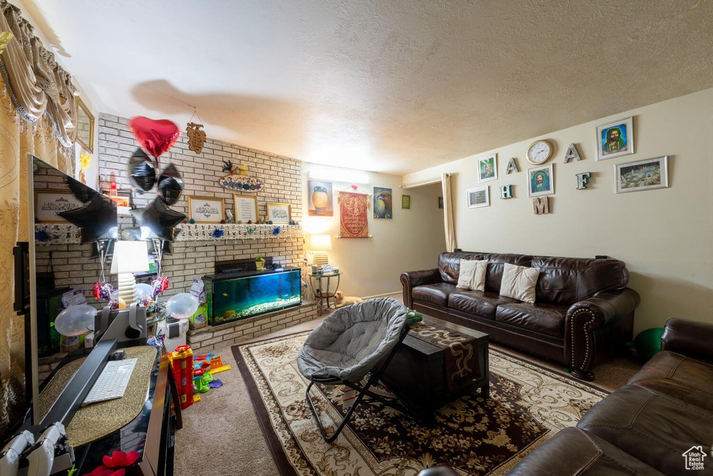 Living area featuring a fireplace, carpet flooring, brick wall, and a textured ceiling