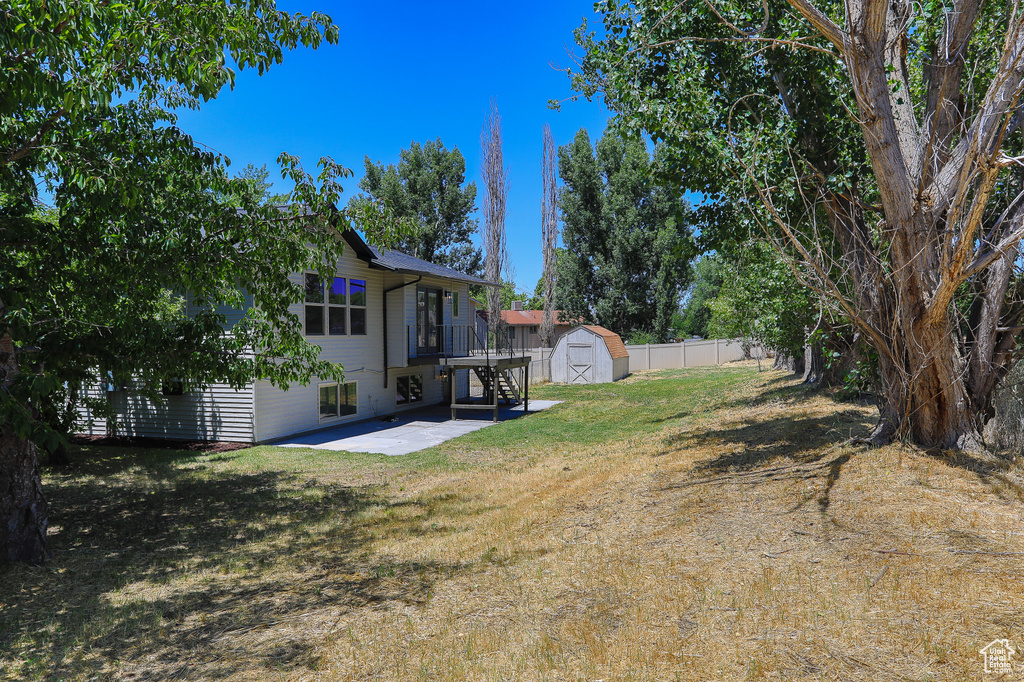 View of yard featuring a shed, a patio, and a deck
