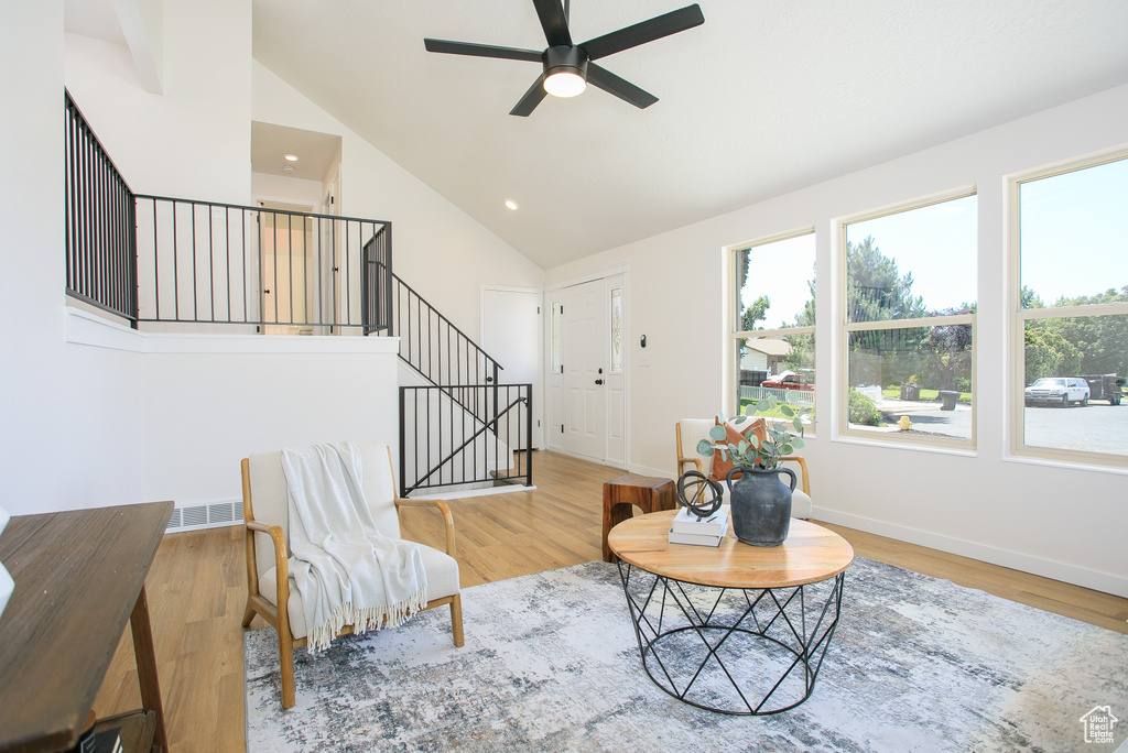 Living room with ceiling fan, wood finished floors, stairs, recessed lighting, and high vaulted ceiling