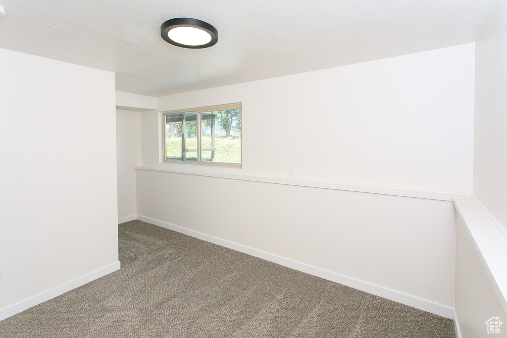 Carpeted spare room featuring baseboards