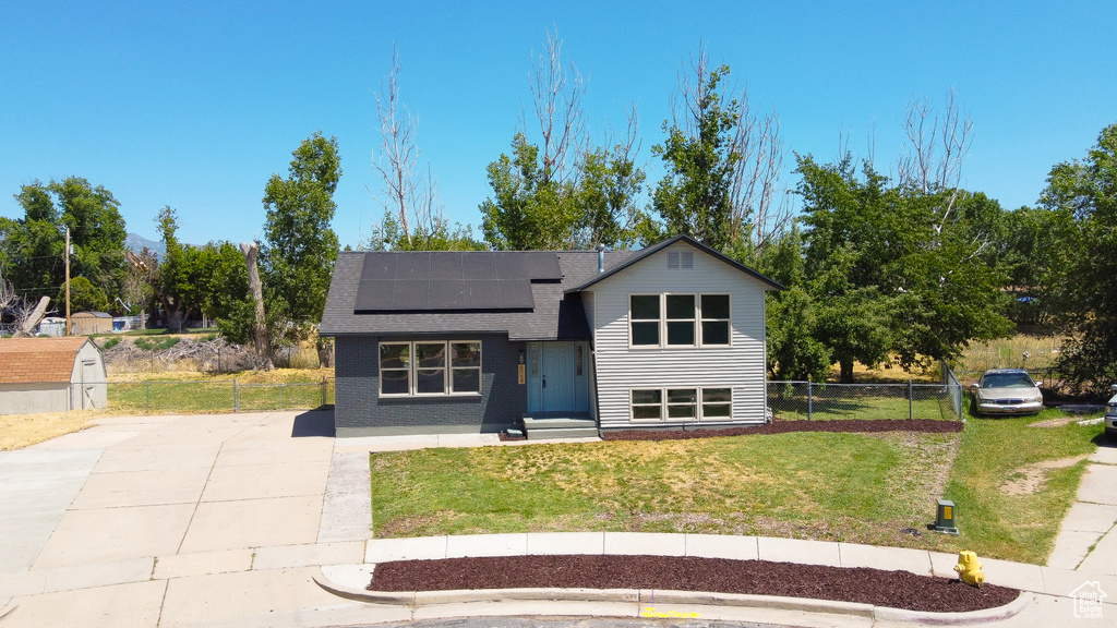 View of front of house with roof mounted solar panels and roof with shingles