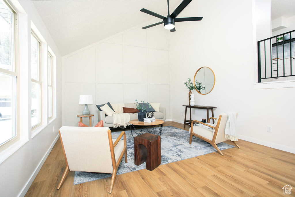 Sitting room with wood finished floors, plenty of natural light, a ceiling fan, and high vaulted ceiling
