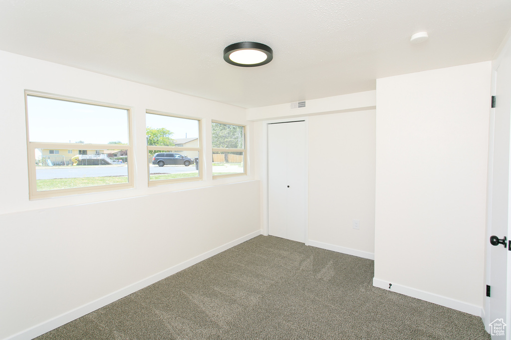 Unfurnished bedroom featuring dark colored carpet and a closet