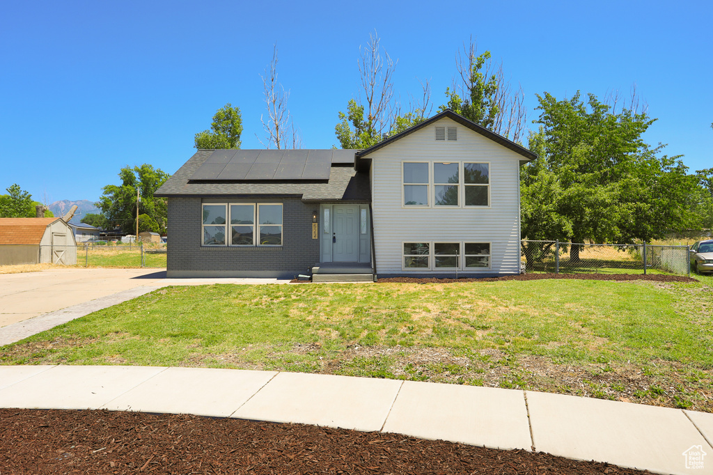 Split level home featuring roof mounted solar panels and a shingled roof