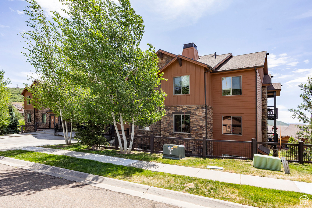 View of home's exterior with stone siding, a fenced front yard, a chimney, and board and batten siding
