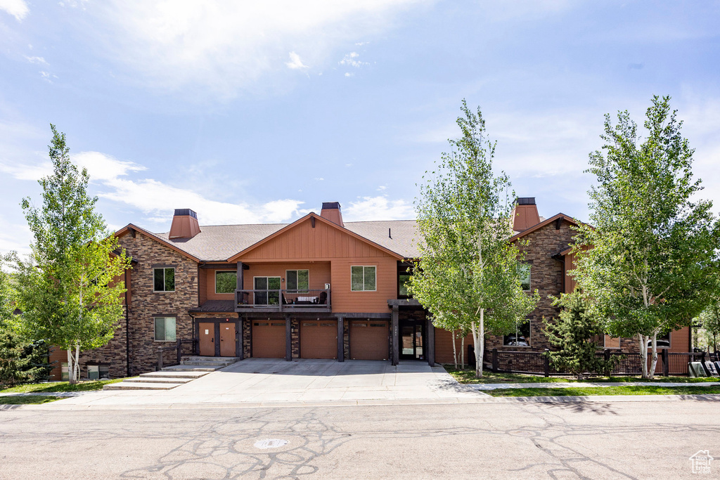 View of property with stone siding, a garage, and a chimney