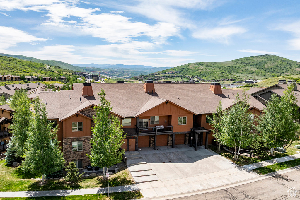 View of front of house with a garage, stone siding, concrete driveway, roof with shingles, and a mountain view